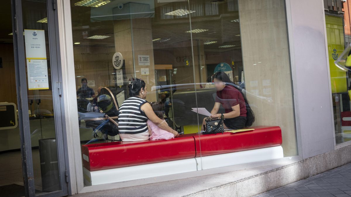 Una familia espera su turno para presentar la regularización en una oficina de Correos