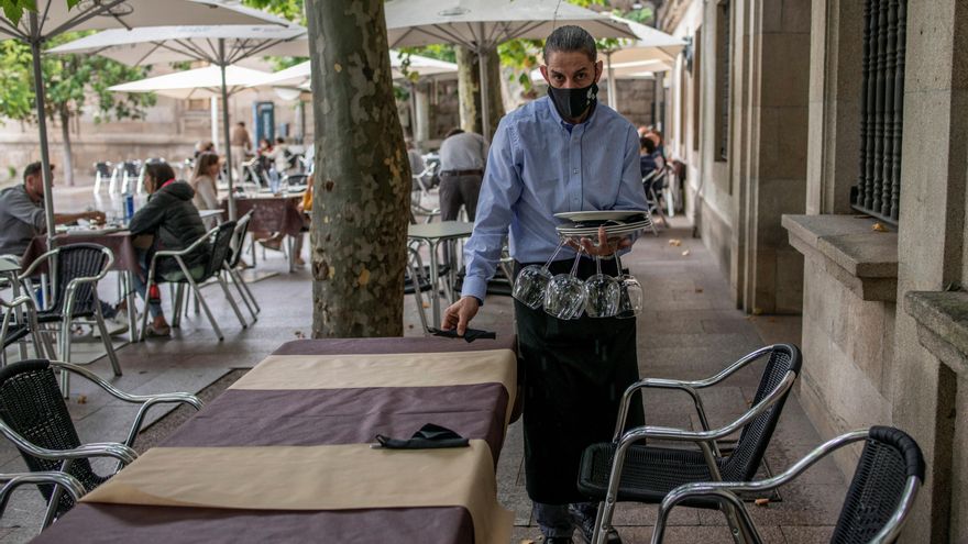 Un camarero recoge una mesa en la terraza de su restaurante, en Orense. EFE/Brais Lorenzo/Archivo