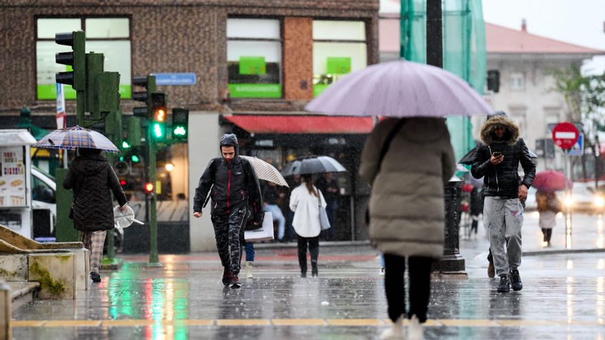Archivo - Varias personas con paraguas cruzan un paso de cebra en Santander.-ARCHIVO