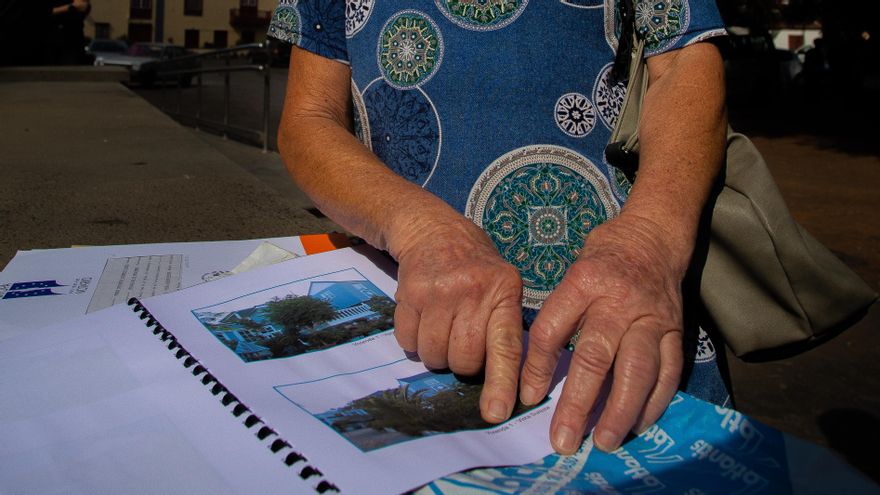 Carmen señala las fotos de su vivienda de El Paraíso, sepultada por la lava