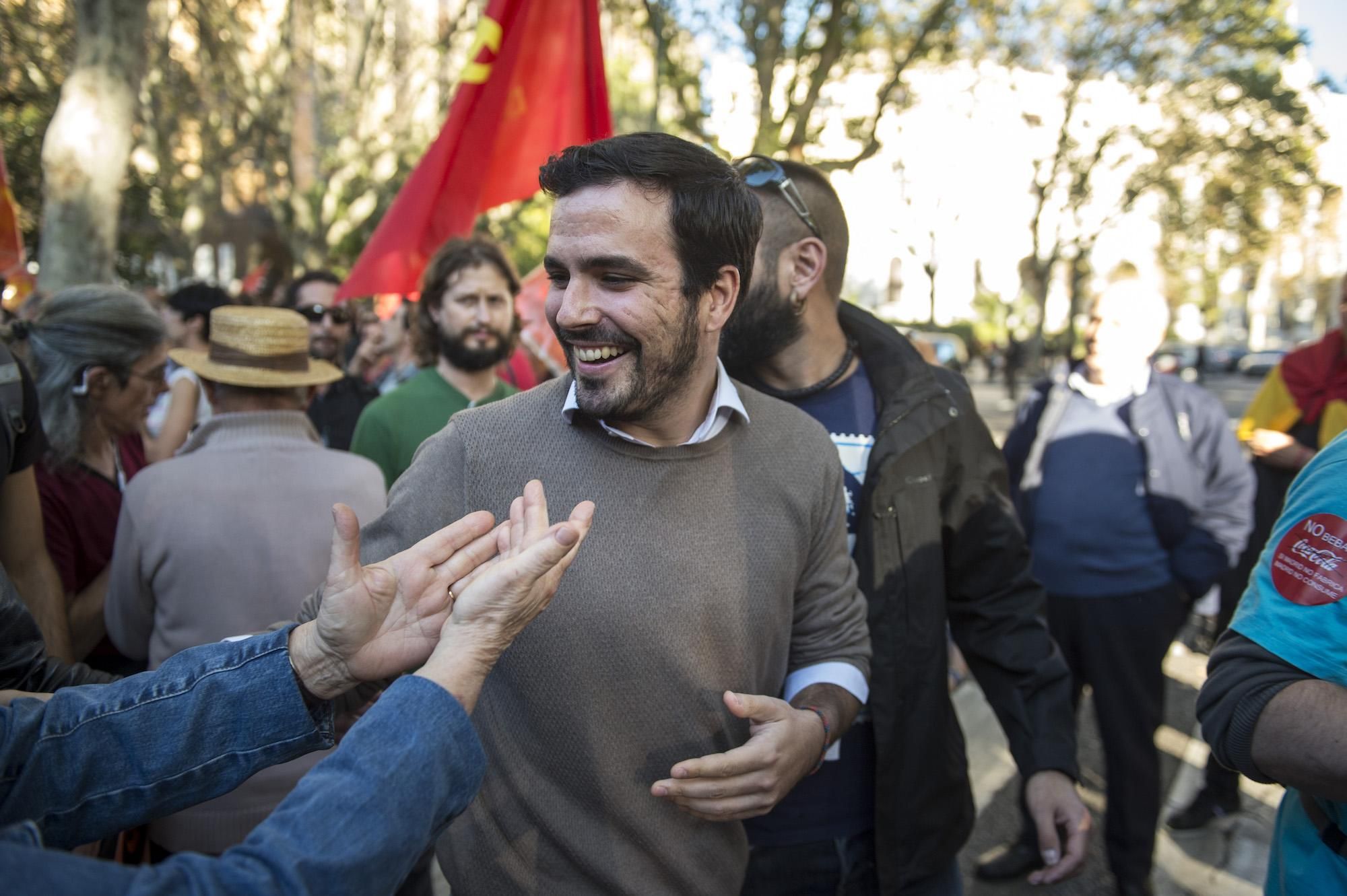 El diputado de Unidos Podemos, Alberto Garzón, saluda a los manifestantes que abarrotan el Paseo del Prado, minutos antes de dar comienzo el pleno