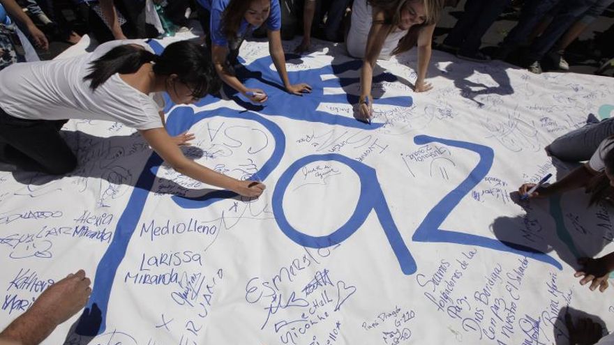 Salvadoreños escriben en un cartel durante una actividad para formar el símbolo de la paz en el estadio Cuscatlán en San Salvador (El Salvador).