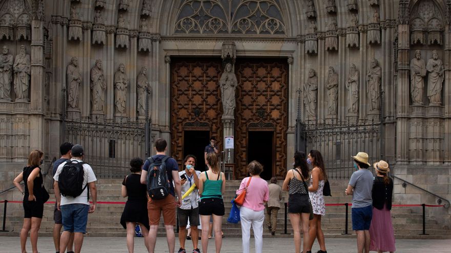 Un grupo de turistas atiende a las explicaciones de su guía, ante la Catedral de Barcelona. EFE/Enric Fontcuberta/Archivo