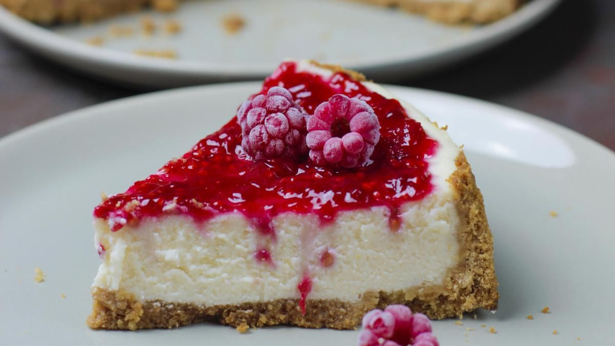Porción de tarta de queso decorada con mermelada y frutos rojos