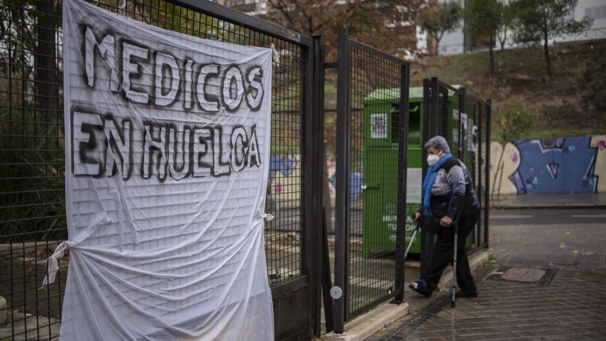 Una mujer entra al centro de salud Numancia, en Vallecas, donde hay una pancarta colgada donde se lee "Médicos en huelga".