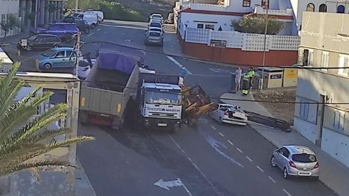 Los dos camiones accidentados y el brazo de la grúa, sobre el coche que estaba aparcado