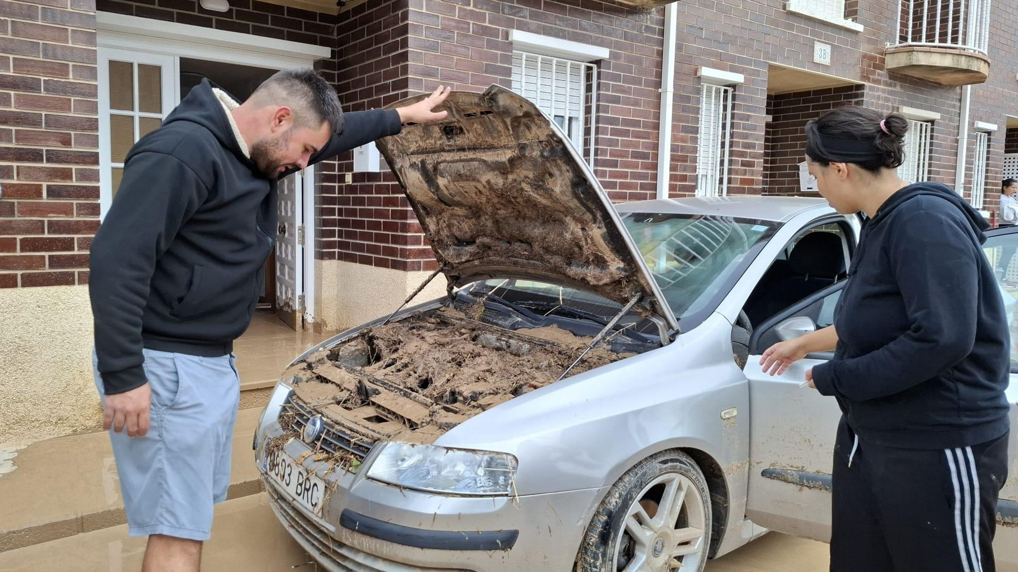 Los propietarios de un vehículo examinan los daños causados.
