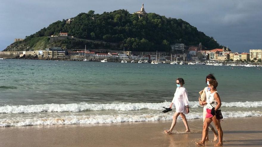 Tres mujeres, con mascarilla, pasean este jueves por la playa de la Concha de Donostia