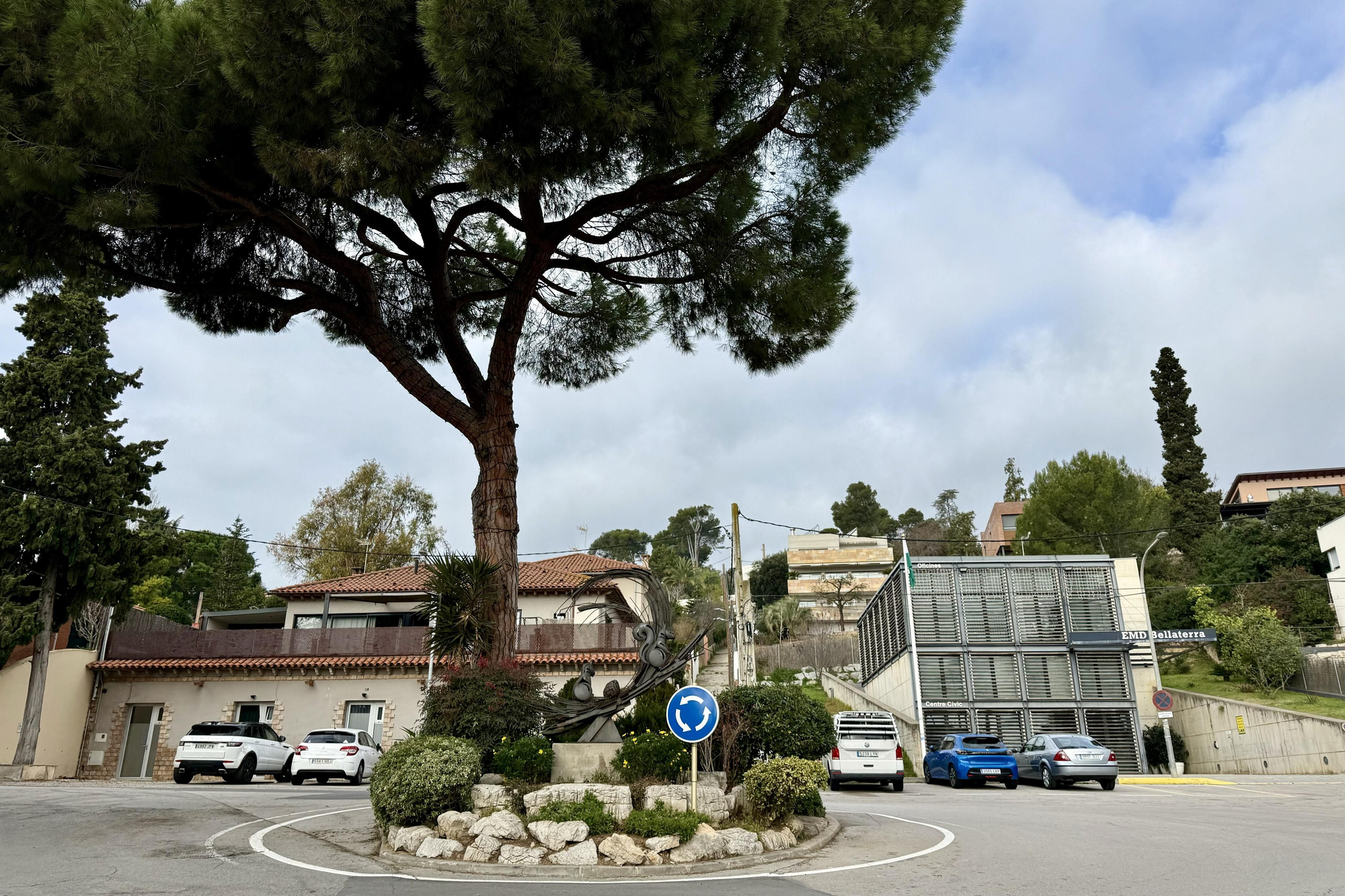 Una rotonda de Bellaterra y, al fondo, la sede oficial de la Entidad Municipal Descentralizada (EMD)
