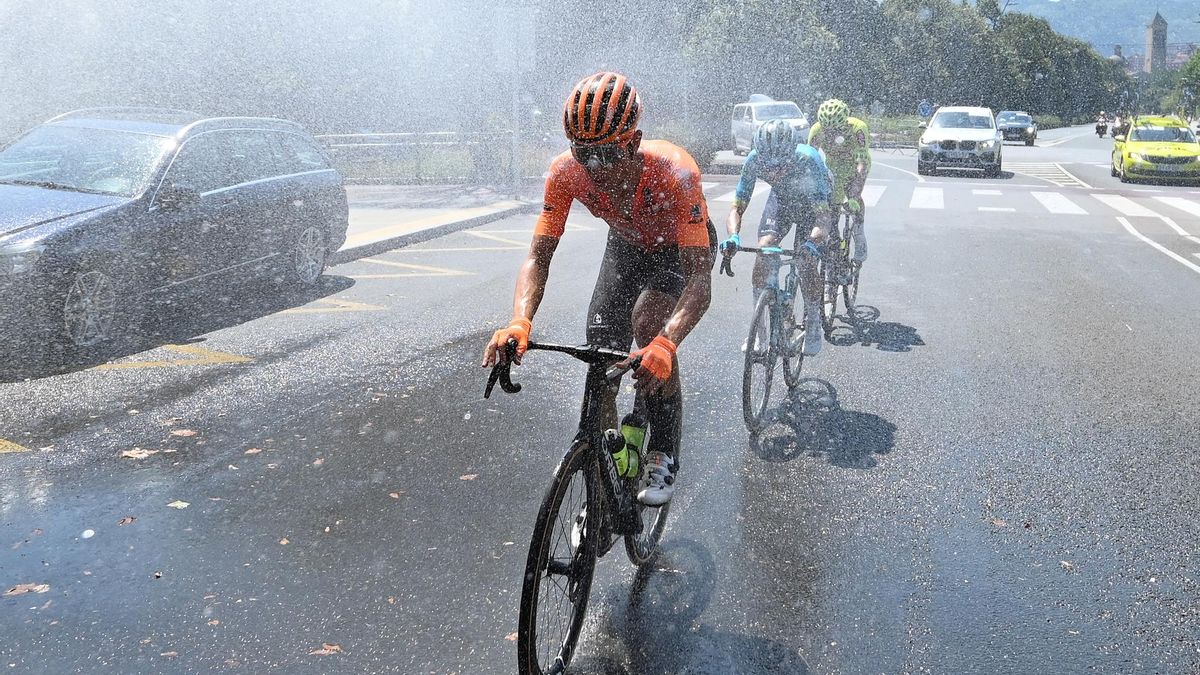 Ciclistas pasando bajo las mangueras en Getxo para combatir el calor