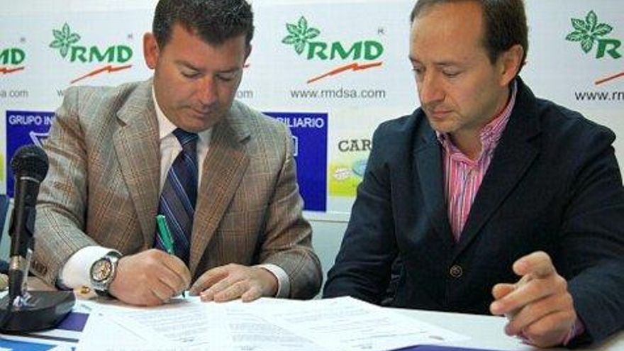 Javier Baena firmando el contrato junto a Javier Fuentes.
