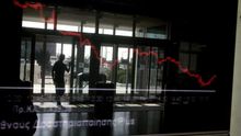 Reflejo de una pantalla con la caída bursátil en la entrada de la Bolsa de Atenas.