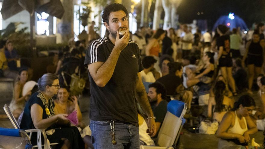 Un joven come un 'pa amb oli' mientras mira a la cámara.