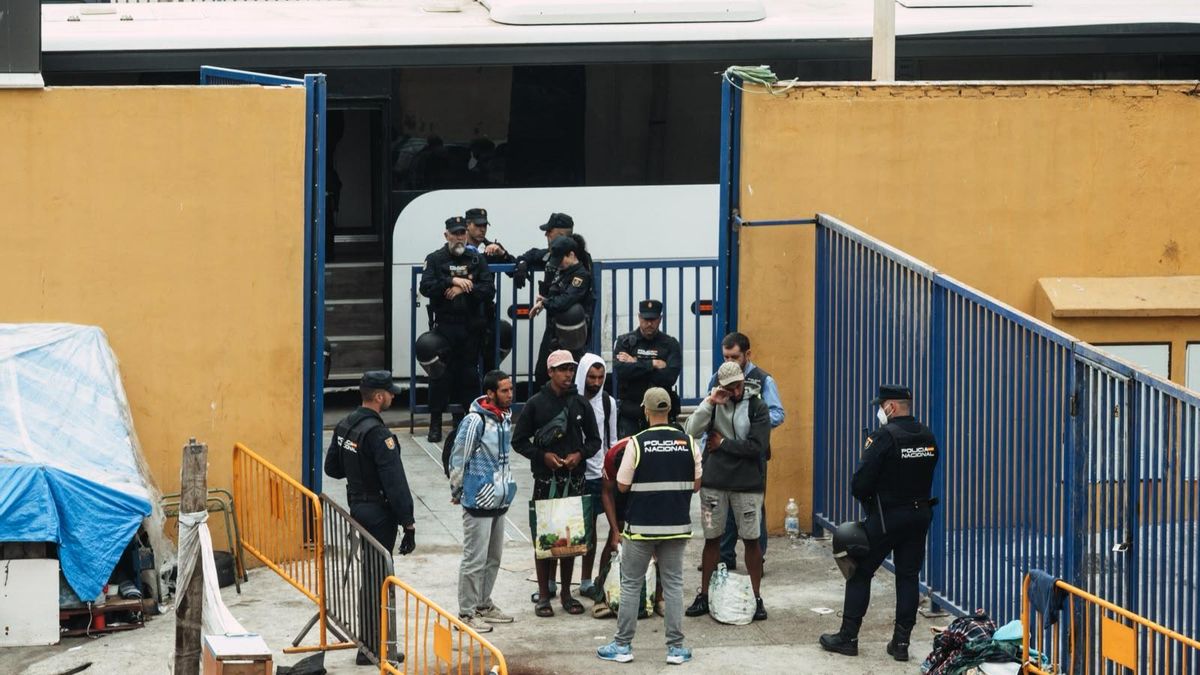 Migrantes escuchan las explicaciones de un policía que habla árabe en la puerta que conecta las naves con la frontera, antes de ser identificados.