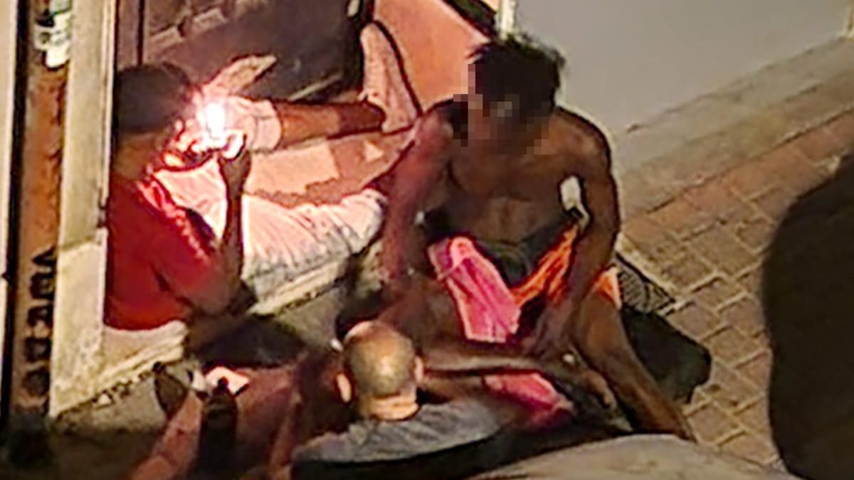 Tres hombres consumiendo droga en el portal de un edificio