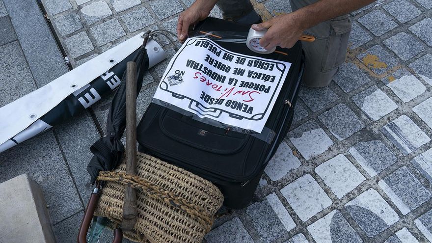 Un manifestante pega un cartel a su maleta.