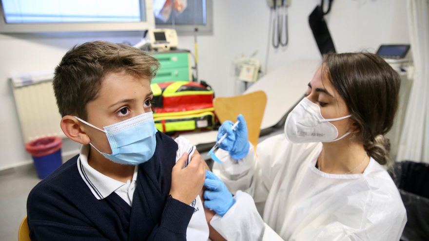 Una sanitaria administra la primera dosis de la vacuna contra la COVID-19 a un niño.