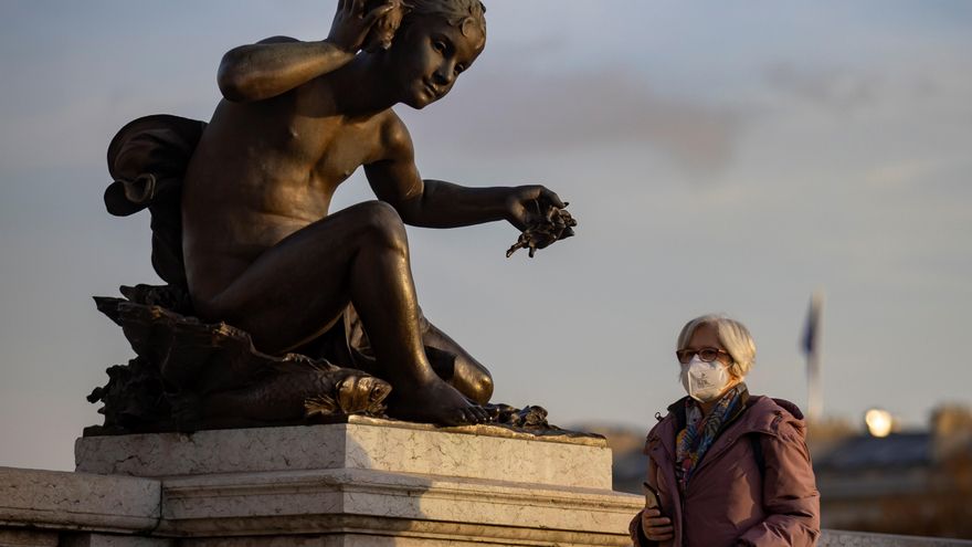 Una mujer con mascarilla protectora camina por el Puente Alexandre III este jueves en París. EFE/IAN LANGSDON