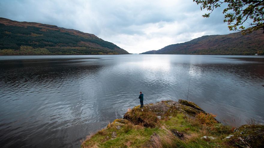 Un hombre pesca en las orillas de Loch Lomond.