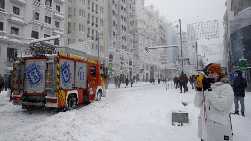 Varias personas pasean por la Gran Via cubierta de nieve en Madrid, este sábado. EFE/ Ballesteros