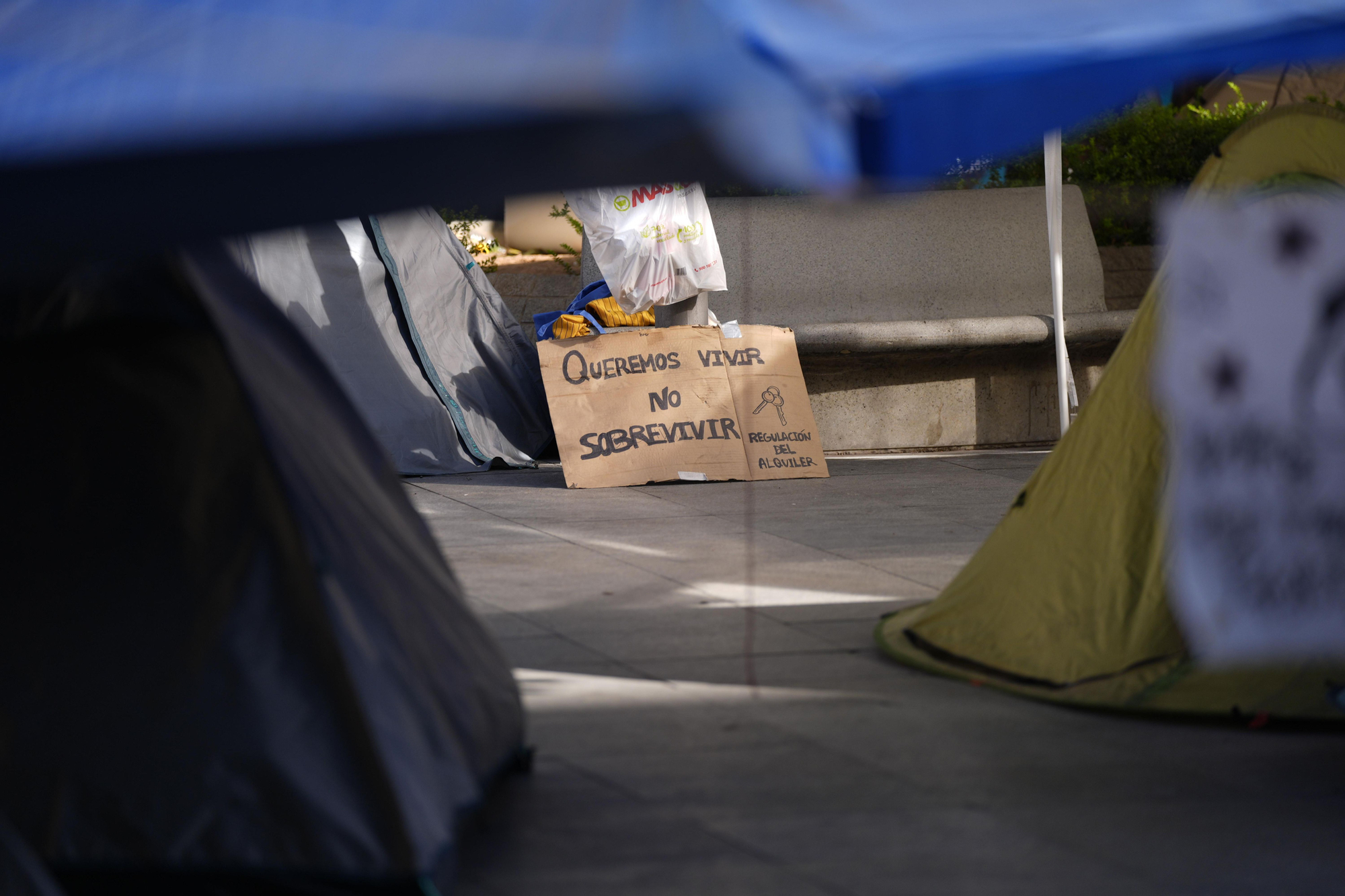 Un cartel con el lema "Queremos vivir, no sobrevivir", en la acampada por la vivienda de Sevilla