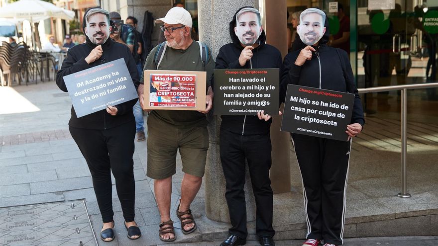 Familiares de los afectados protestan este martes contra la "criptosecta" con un cartel que pone "han lavado el cerebro a mi hijo y le han alejado de su familia y amig@s", en Madrid.