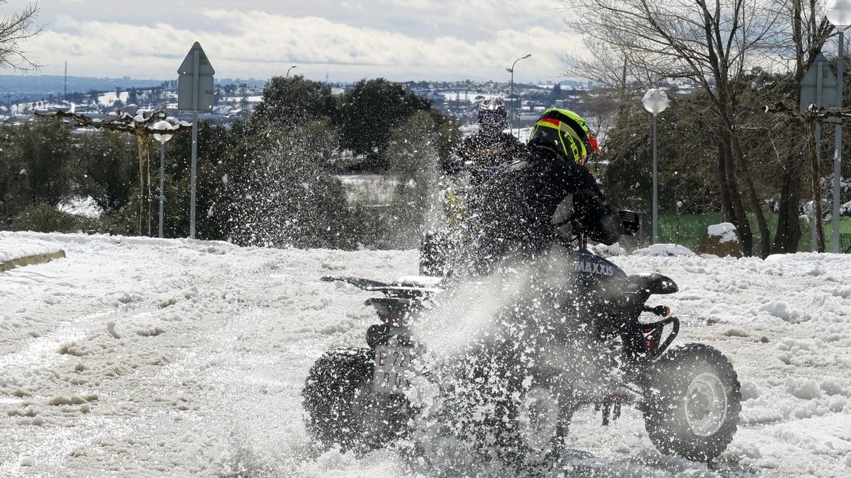 Dos personas juegan en la nieve montadas en quads este miércoles en El Vellón (Madrid)