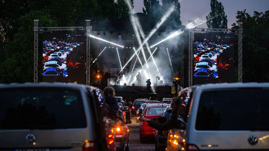La gente se queda dentro de sus coches mientras una banda toca en el escenario durante un concierto en el área abierta de Ostrava, República Checa.