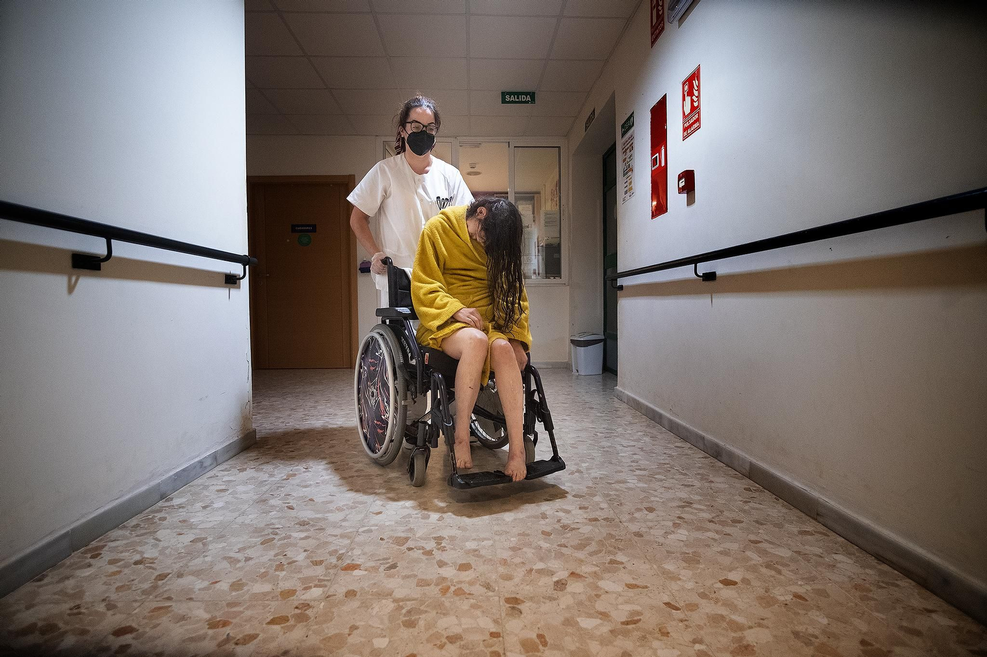 Una trabajadora acompaña a Inés a su cuarto después de la ducha