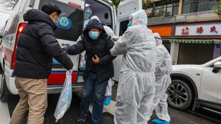 Personal médico totalmente protegido ayuda a un paciente a salir de la ambulancia en el exterior del hospital en Wuhan, provincia de Hubei, China.