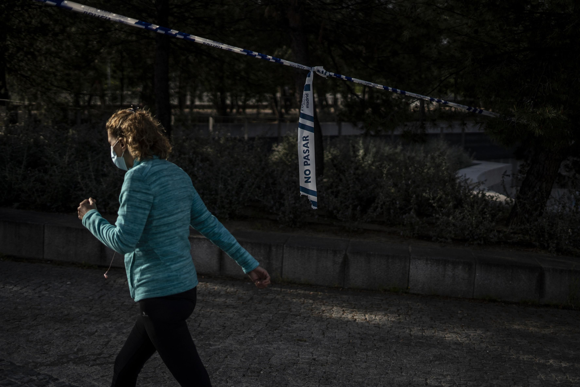 Una mujer avanza mientras hace deporte por debajo de una cinta que limita el paso