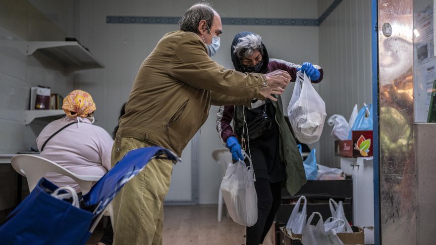 Julián recoge una bolsa de alimentos del reparto organizado por la asociación de vecinos de Campamento (Madrid) y los comerciantes del mercado