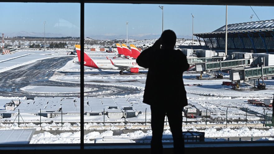 Un viajero toma fotos de las pistas en la Terminal 4 del aeropuerto Adolfo Suárez Madrid-Barajas cubiertas parcialmente de nieve este lunes en Madrid. EFE/Fernando Villar