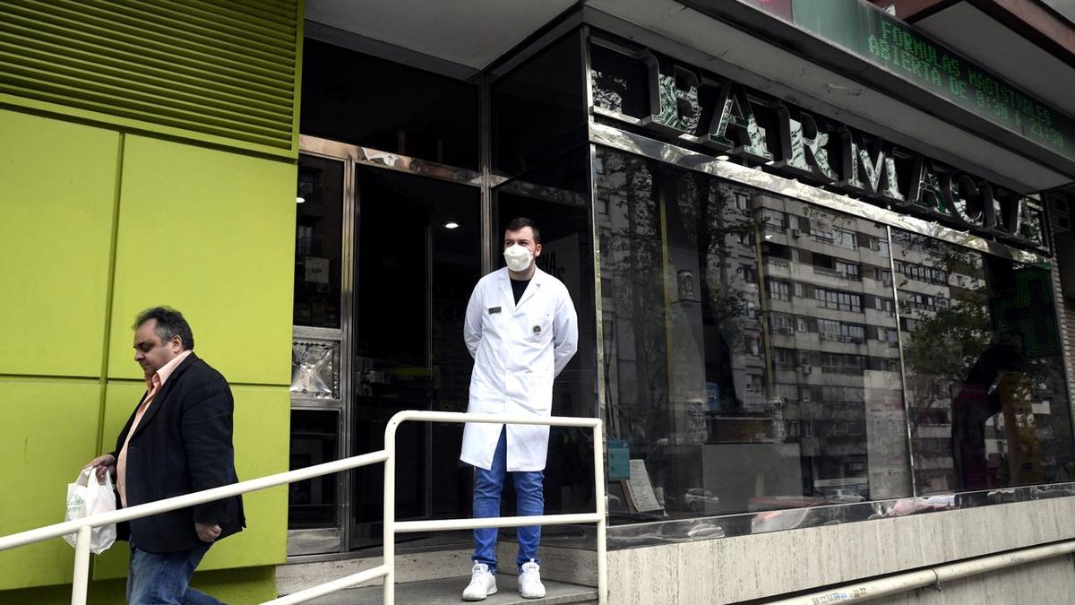 Un farmacéutico protegido con mascarilla en la puerta de una Farmacia | ÓSCAR CAÑAS