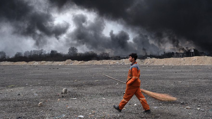 Un barrendero camina por delante del Depósito de Petróleo del Noroeste de Teherán atacado