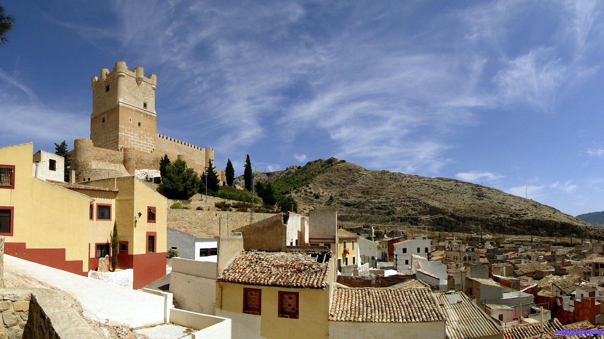 La masa imponente del Castillo de La Atalaya emerge tras los tejados del Raval de Villena.