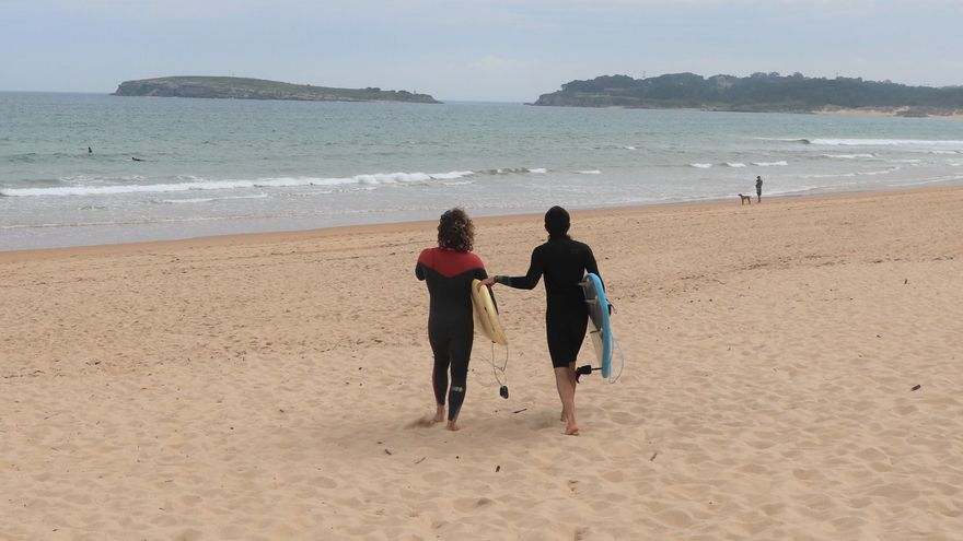 Juanma (dcha) se agarra a la tabla de Claudio (izq) para llegar al agua.