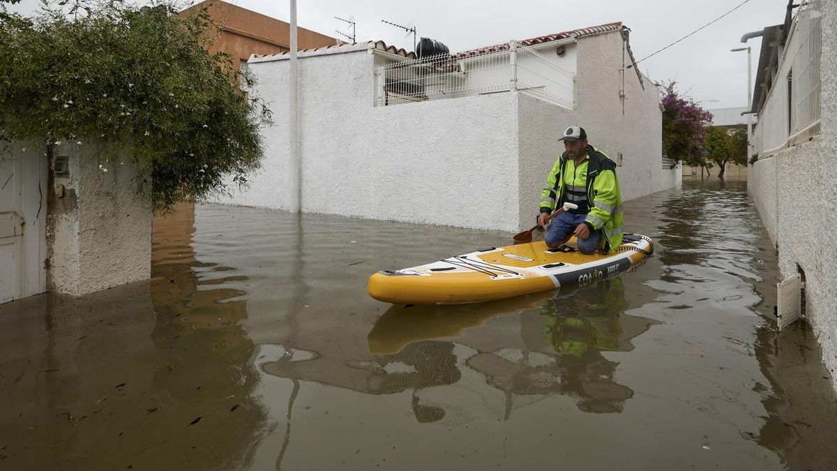 Un hombre se desplaza sobre una tabla de padel surf en la zona residencial próxima a la playa de Venecia, en el Grao de Gandía este lunes.