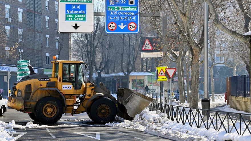 La ciudad de Madrid tiene ya 3.045 de sus 9.261 calles limpias de nieve, lo que supone un total de 2.100 kilómetros despejados, y más de 3.000 calles abiertas parcialmente, mientras que 96 líneas de autobús urbano de las más de 200 que operan habitualmente ya circulan por la capital. En la imagen, una excavadora limpia la plaza de El Encuentro, en los accesos a la M-30 y la A3, en el distrito de Moratalaz. EFE/Víctor Lerena