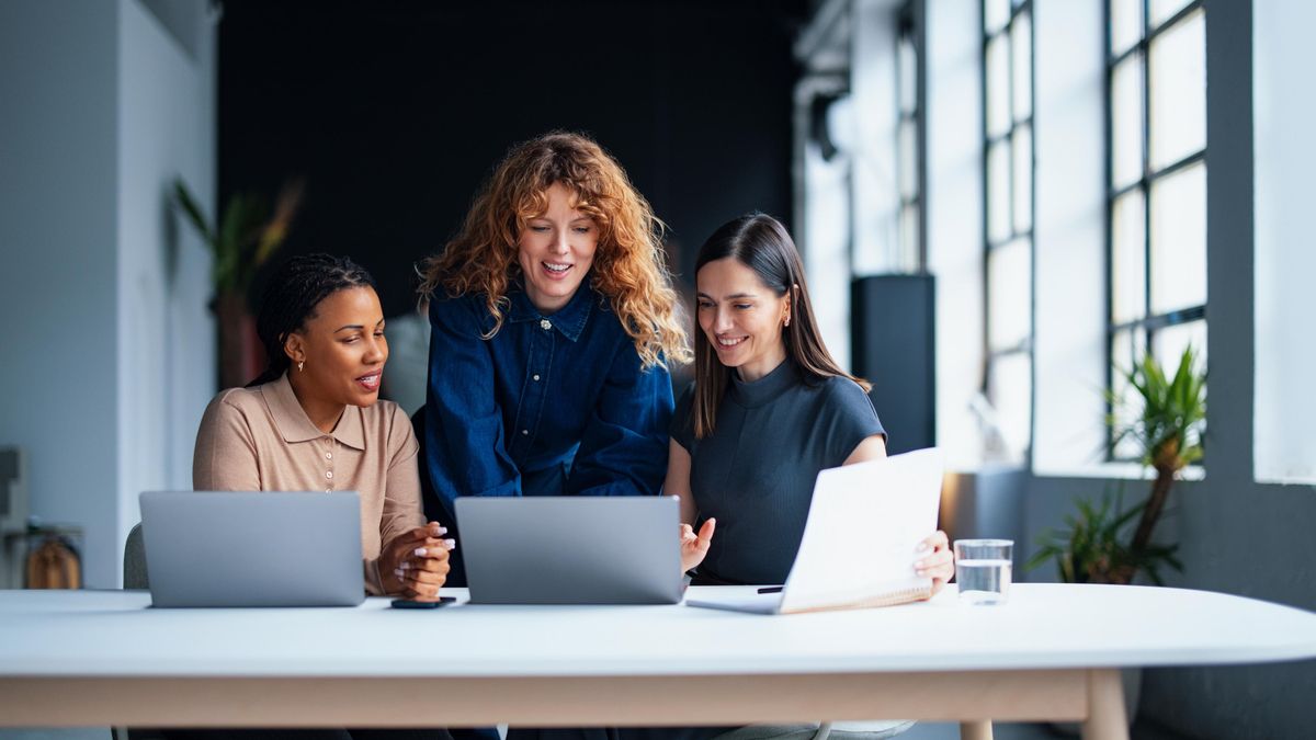 Varias compañeras de trabajo consultan sus ordenadores.