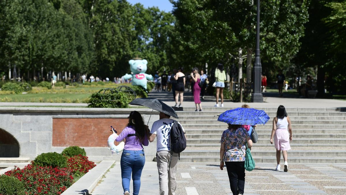 Varias personas se protegen del sol en el Parque de Retiro de Madrid en imagen de archivo.