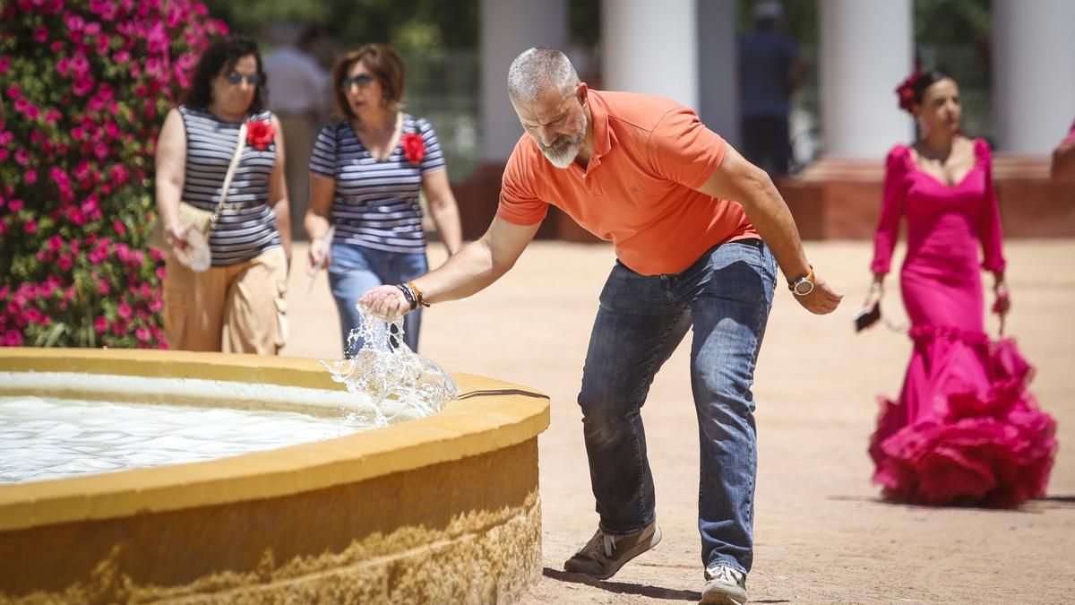 Un hombre se refresca en una fuente de la Feria