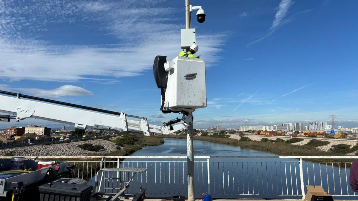 Un operario instala una de las cámaras en un puente sobre el río Túria.