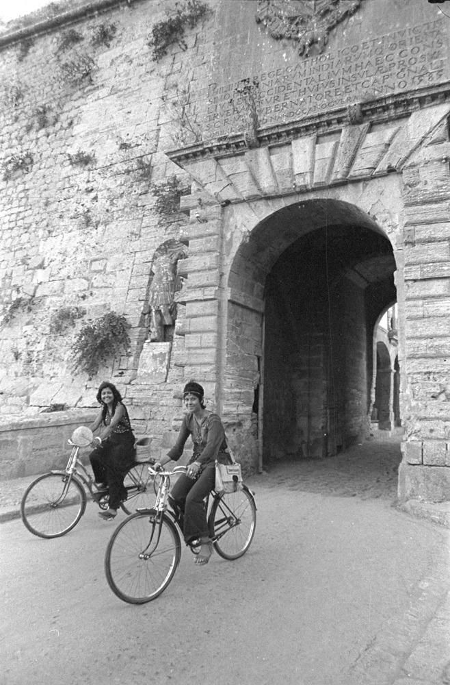 Dos chicas descienden con sus bicis por el Portal de ses Taules, la entrada principal de las murallas renacentistas de Dalt Vila.