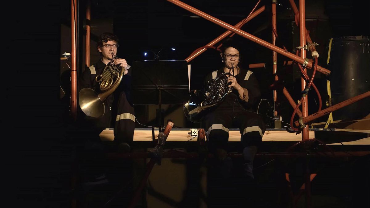 Dos músicos tocando el corno, vestidos con mamelucos de trabajo, en la instalación audiovisual Geonnitus el pasado marzo en Buenos Aires.