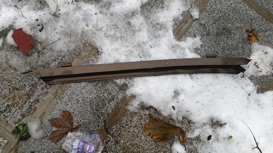 Trozo de metal que señala otro vecino, que podría ser parte de un marco de ventana