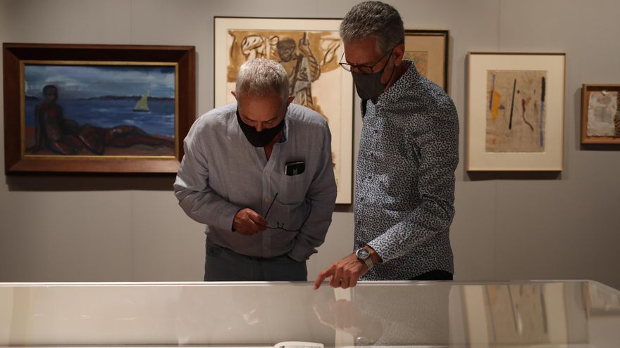 El comisario de la muestra, José Vicente Plaza, y el hermano de Carmen Alborch observan los documentos expuestos.