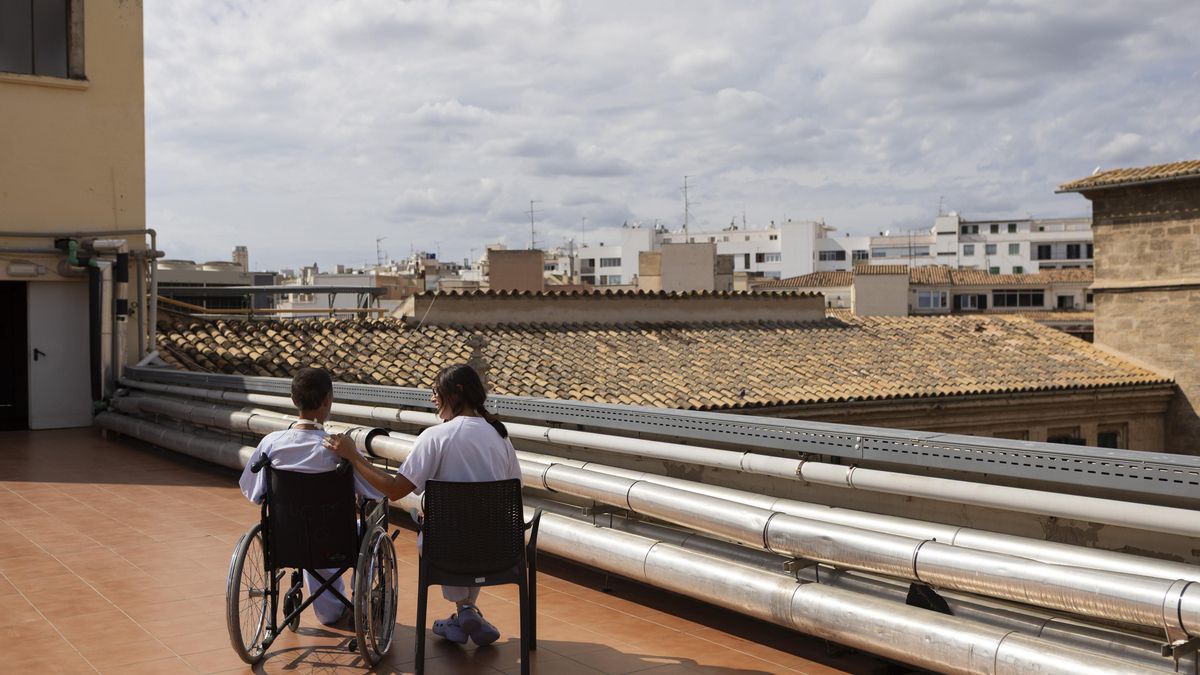 Antonio, acompañado por una de las enfermeras en la terraza del Hospital General, donde comparten el día a día con sus familiares y con los profesionales que cuidan de ellos