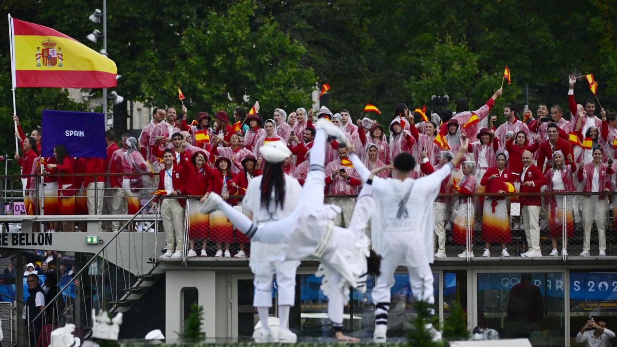 Bailarines actúan sobre plataformas flotantes mientras los atletas de la delegación española navegan en un barco por el río Sena