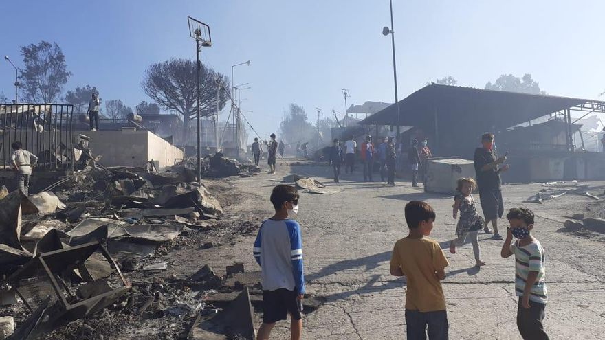 Niños con mascarillas pasean por los restos calcinados.
